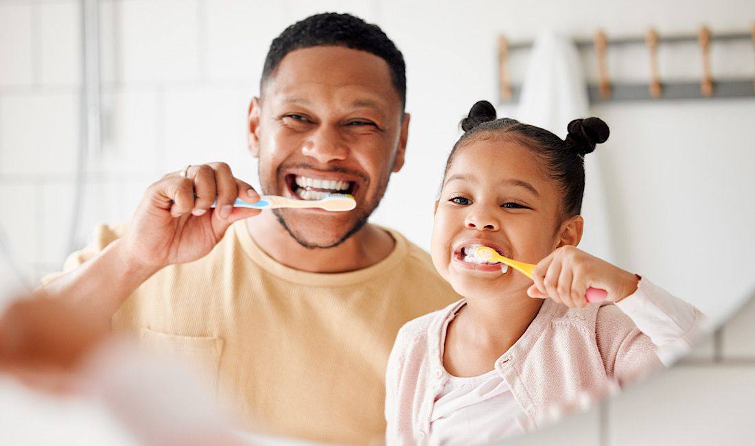Father and daughter brushing their teeth together