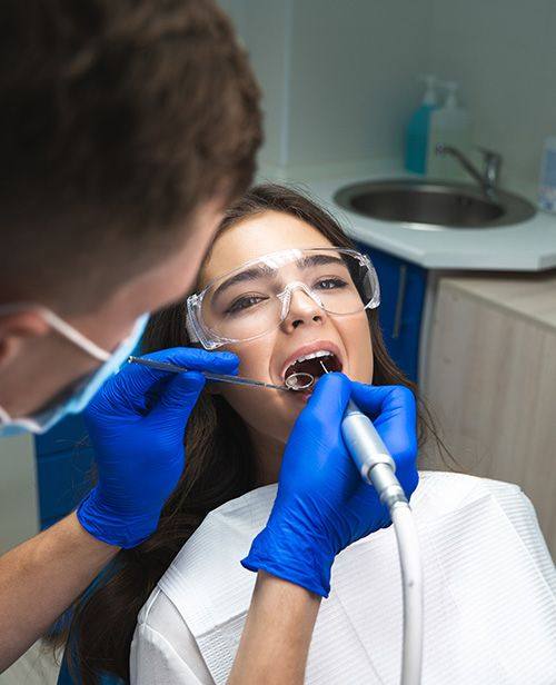 Dentist treating a woman wearing protective glasses