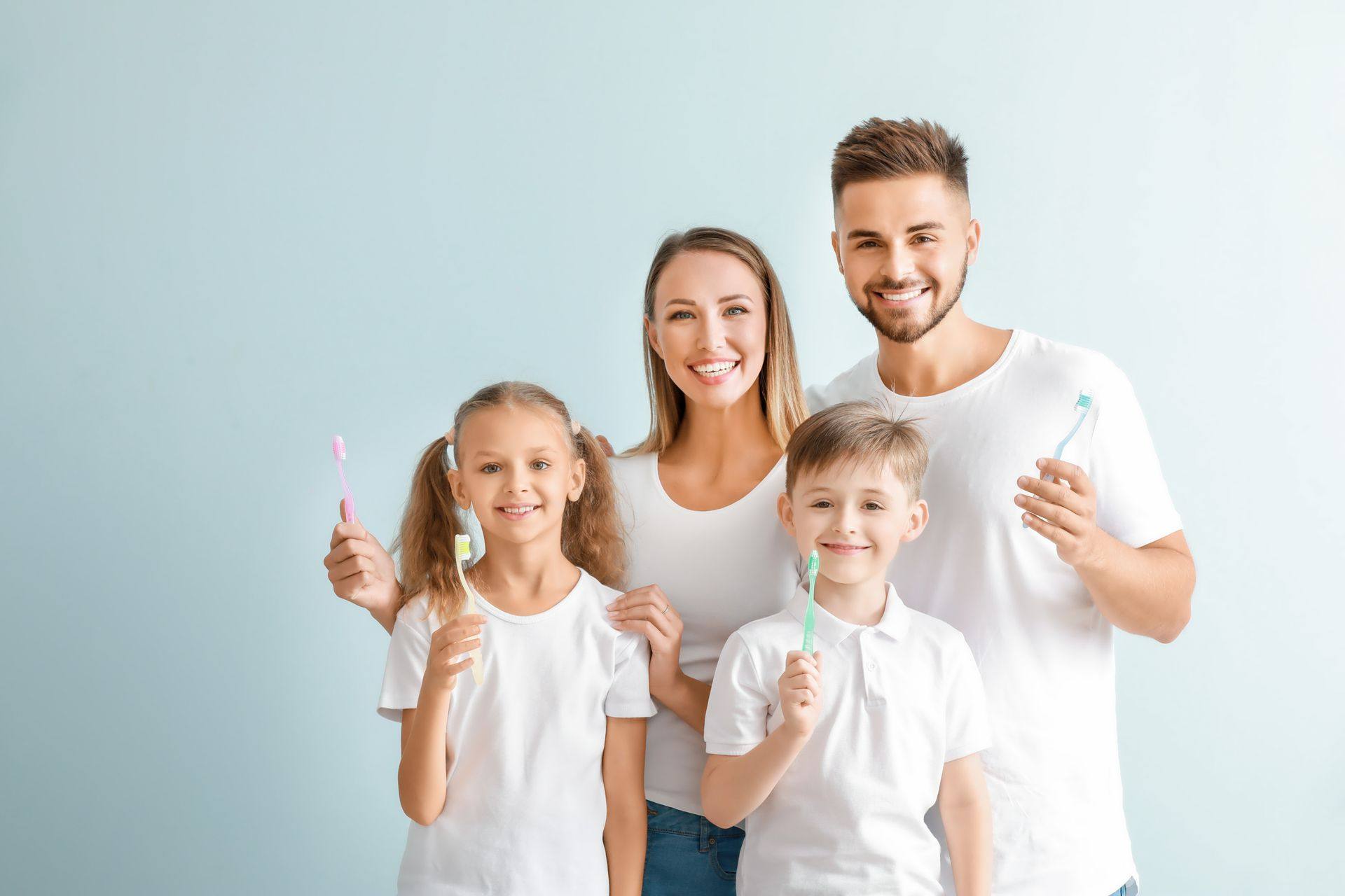 Smiling family of four holding toothbrushes