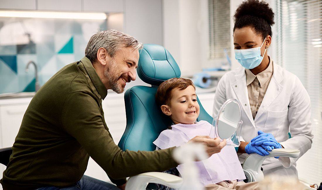 Father and son talking with a dentist at a pediatric checkup