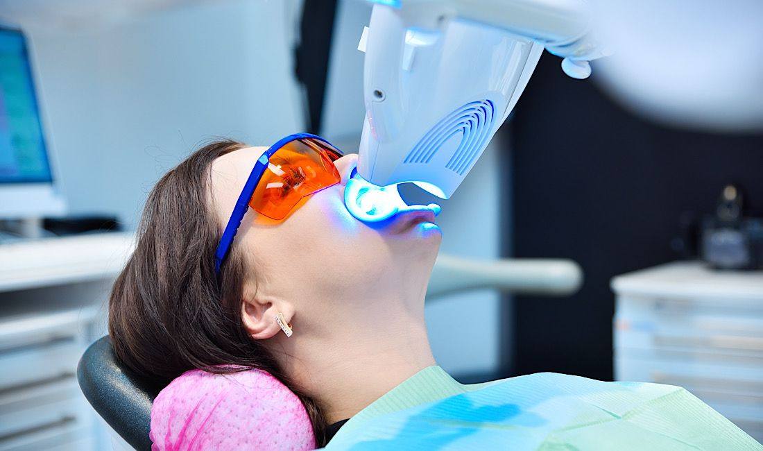 Woman receiving in-office whitening under a blue light