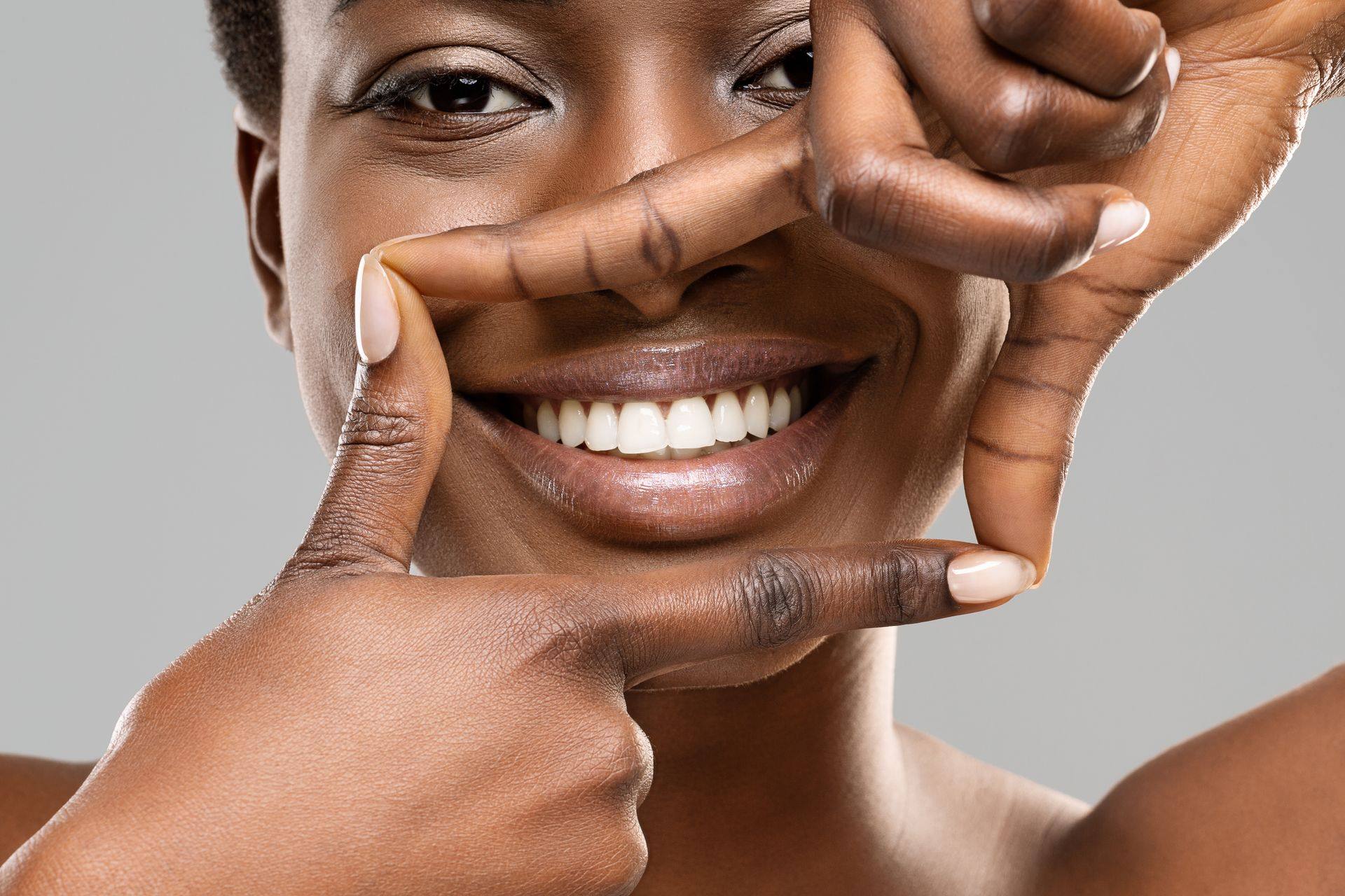 Woman framing her bright smile with her fingers