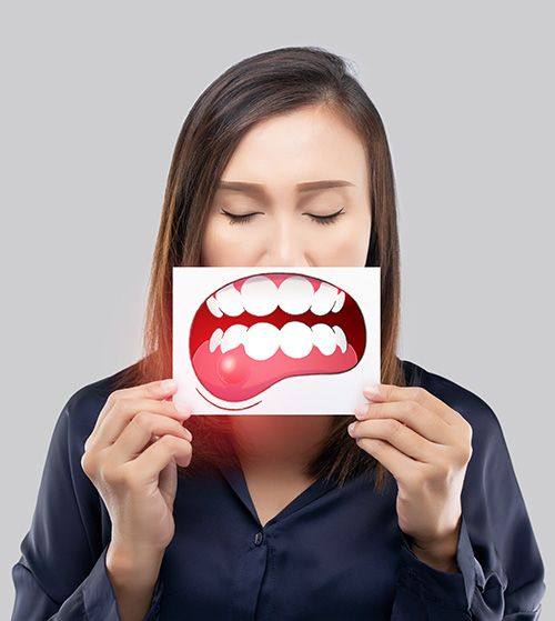 Woman holding a card with a drawing of red, swollen gums in front of her mouth