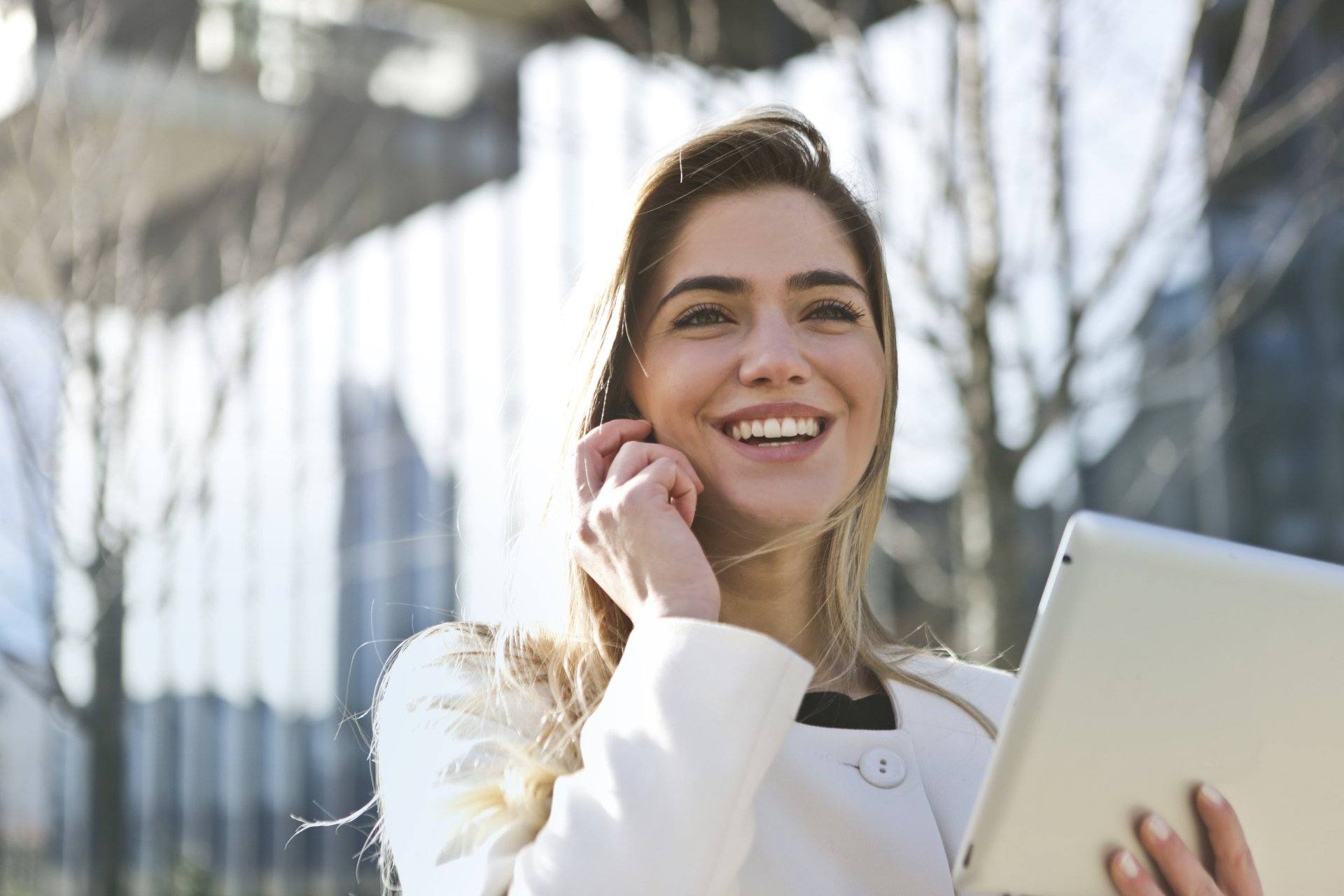 Smiling woman talking on the phone and holding a tablet